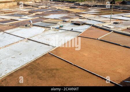 Blick auf die Salinen in Rio Maior, Portugal, mit Salzarbeiter, die das Salz mit einer Schaufel verbinden. Stockfoto