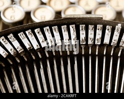 Die Eisenhämmer einer alten Schreibmaschine mit den Tasten im Hintergrund verschwommen. Typisierung und veraltete Technologie. Vintage-Objekt Stockfoto