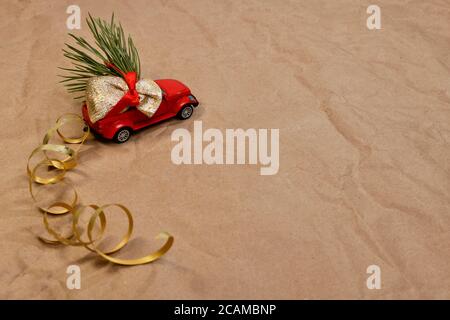 Der Spielzeug-Pickup-Truck trägt eine Geschenktüte, einen Weihnachtsbaum. Vorderansicht schräg linker Grundriss auf braunem Papier. Stockfoto
