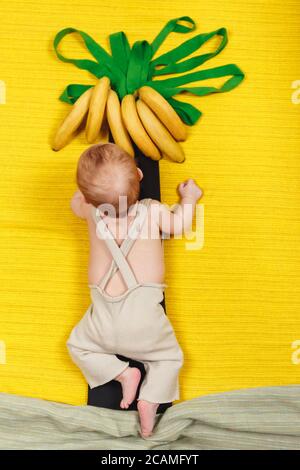 Glückliches Kind will Bananenfrucht haben. Palme mit wachsenden Bananen Stockfoto
