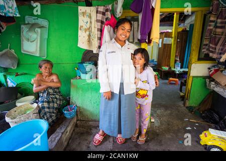 Yogyakarta / Indonesien - 2. August 2018: Portrait von zwei Schwestern und Großmutter, die mit einem Becken an der Tür ihres Hauses baden Stockfoto