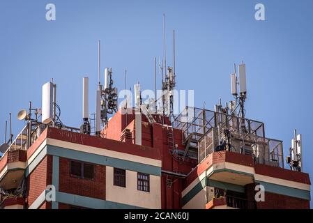 Antennen der Mobilfunk-Basisstation über den Dächern von Ein Gebäude Stockfoto
