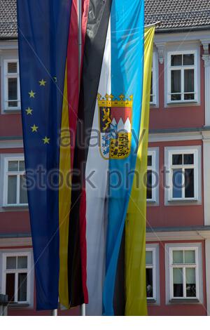 Vier Flaggen hängen im Sonnenschein auf dem Rathaus von Coburg in Bayern, die EU-Flagge, die deutsche Flagge sowie die bayerische und die Coburger Flagge. Stockfoto