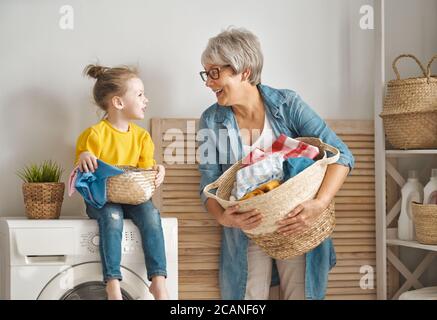 Glückliche Oma und Kind Mädchen kleinen Helfer haben Spaß und lächeln, während die Wäsche zu Hause. Stockfoto