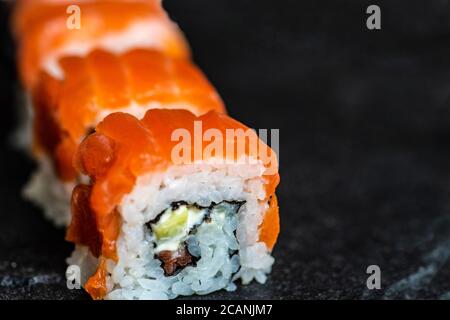 Sushi-Set mit Philadelhia-Brötchen auf Steintisch serviert mit Essstäbchen Stockfoto
