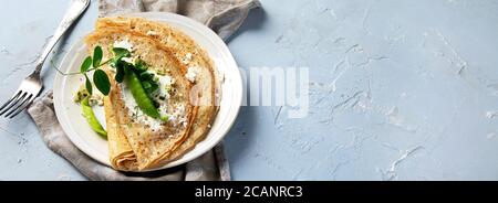 Appetitlich Crepe nicht süße Crepes. Mit Pesto und Riccota auf grauem Hintergrund. Leckere Crepes, dünne Pfannkuchen. Leckeres Frühstück. Draufsicht, flach liegend, b Stockfoto