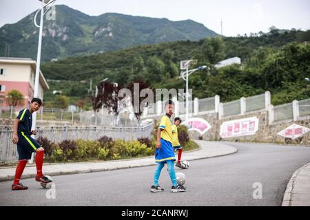 Weining, Chinas Provinz Guizhou. August 2020. Die Spieler der Fußballmannschaft "Green Pepper" gehen zu einer Trainingseinheit an der Shimen Minzu Mittelschule in den autonomen Bezirken Yi, Hui und Miao in Weining, südwestlich von Chinas Provinz Guizhou, 7. August 2020. Über 40 lokale Studenten bildeten eine Fußballmannschaft namens "Green Pepper" und widmeten sich dem Fußballtraining während der Sommerferien in Shimen Township in Weining County, einem ländlichen Ort mit einer durchschnittlichen Höhe von über 2,000 Metern. Quelle: Liu Xu/Xinhua/Alamy Live News Stockfoto
