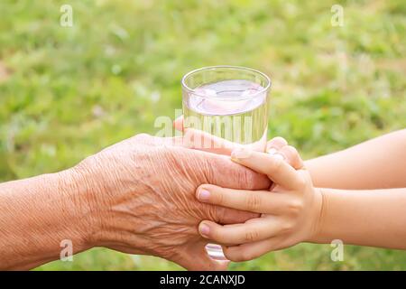 Großmutter gibt einem Kind ein Glas sauberes Wasser. Selektiver Fokus. Stockfoto