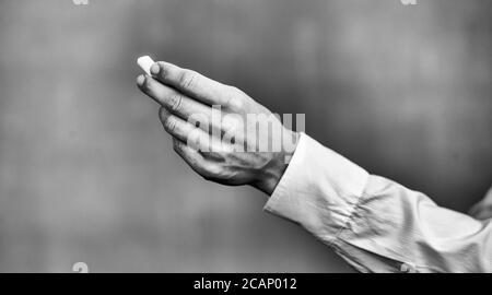 Lehrerin erklärt Schulunterricht an der Tafel. Detail auf der Hand hält ein Stück Kreide. Zurück zur Schule Konzept. Stockfoto