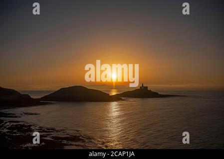 Murmbles, Swansea, Großbritannien. August 2020. Die Sonne geht heute Morgen über dem Mumbles Lighthouse in der Nähe von Swansea auf, zu Beginn eines atemberaubenden Sommertages in Großbritannien. Quelle: Phil Rees/Alamy Live News Stockfoto