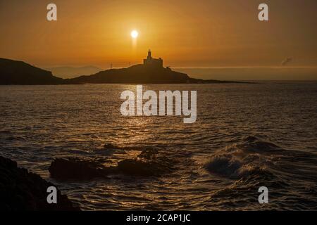 Murmbles, Swansea, Großbritannien. August 2020. Die Sonne geht heute Morgen über dem Mumbles Lighthouse in der Nähe von Swansea auf, zu Beginn eines atemberaubenden Sommertages in Großbritannien. Quelle: Phil Rees/Alamy Live News Stockfoto