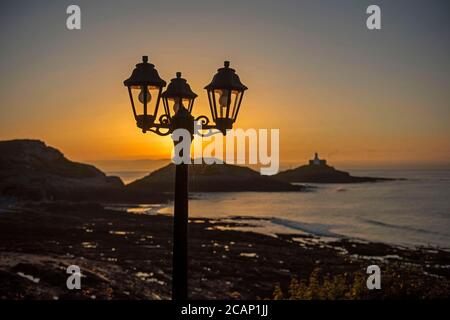 Murmbles, Swansea, Großbritannien. August 2020. Die Sonne geht heute Morgen über dem Mumbles Lighthouse in der Nähe von Swansea auf, wie sie von außerhalb des Castellamare Restaurants zu Beginn eines atemberaubenden britischen Sommertages gesehen wird. Quelle: Phil Rees/Alamy Live News Stockfoto