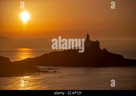 Murmbles, Swansea, Großbritannien. August 2020. Die Sonne geht heute Morgen über dem Mumbles Lighthouse in der Nähe von Swansea auf, zu Beginn eines atemberaubenden Sommertages in Großbritannien. Quelle: Phil Rees/Alamy Live News Stockfoto