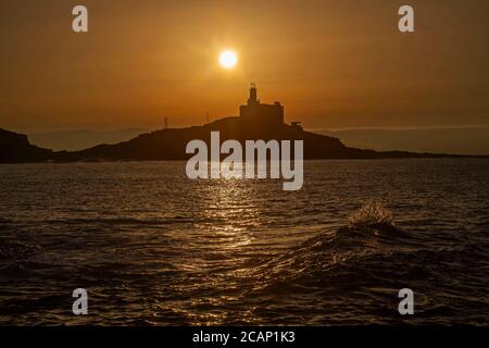 Murmbles, Swansea, Großbritannien. August 2020. Die Sonne geht heute Morgen über dem Mumbles Lighthouse in der Nähe von Swansea auf, zu Beginn eines atemberaubenden Sommertages in Großbritannien. Quelle: Phil Rees/Alamy Live News Stockfoto