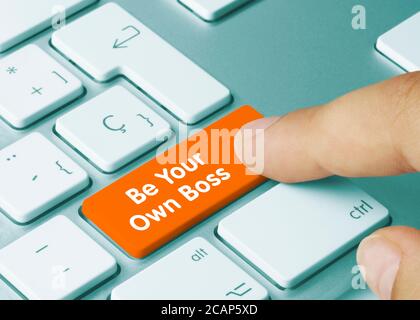 Seien Sie Ihr eigener Boss geschrieben auf Orange Key von Metallic Keyboard. Drücken Sie die Taste mit dem Finger Stockfoto