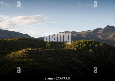 Der Sonnenuntergang am Ende des Tages unterstreicht die Berge, die weiche Kurven mit kontrastreichen Schatten bilden Stockfoto