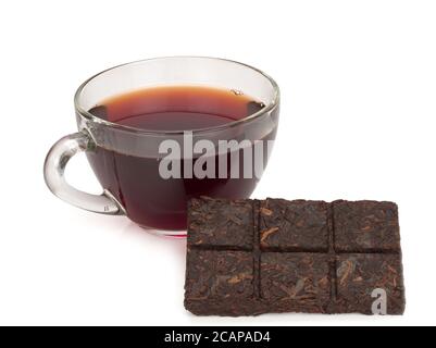 Aromatischer schwarzer pu-erh Tee aus China auf weißem Hintergrund. 5 Jahre alter Tee in Ziegel und in einer Tasse komprimiert. Gesundes Getränk. Stockfoto