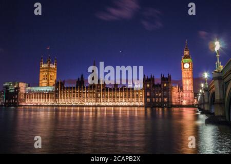 Berühmtes Wahrzeichen, Big Ben Uhrenturm bei Nacht, aufgenommen von der Südseite der Themse im Zentrum von London. Stockfoto