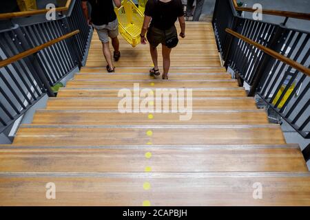 In einem Einkaufszentrum mit Trennzeichen gehen die Menschen eine Holztreppe hinunter. Stockfoto