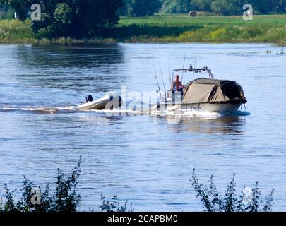 Magdeburg, 27. Juni 2020: Freizeitangler geht mit einem kleinen Motorboot mit angeschlossenem Schlauchboot zum Angelplatz in der Elbe Stockfoto