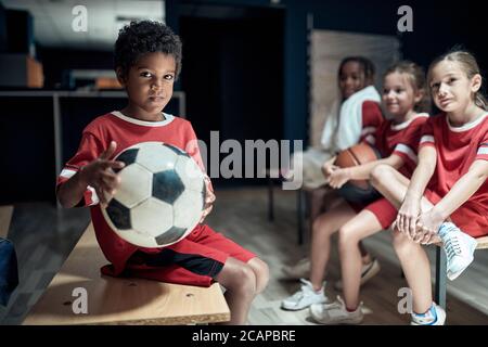 Die kleinen Fußballspieler posieren vor einem Training in einem Umkleideraum Stockfoto