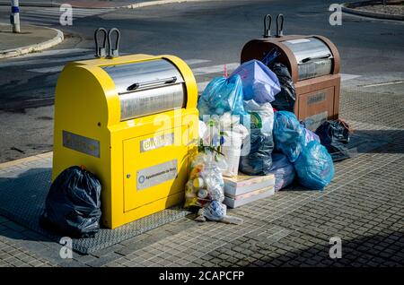 Volle Müll- und Recycling-Mülleimer mit Mülltüten auf dem Boden. Stockfoto