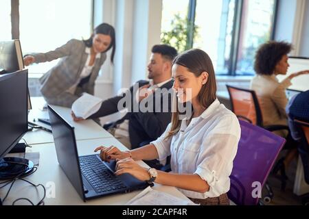 Junge Frau, die im Büro auf dem Laptop arbeitet Stockfoto