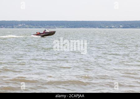 Nowosibirsk, Russland - 07.18.2020: Ein Motorboot mit einer Familie an Bord segeln entlang des Flusses an einem warmen Sommertag. Camping. Stockfoto