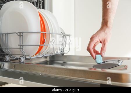 Mann stellt ein Tablet in die Spülmaschine Stockfoto