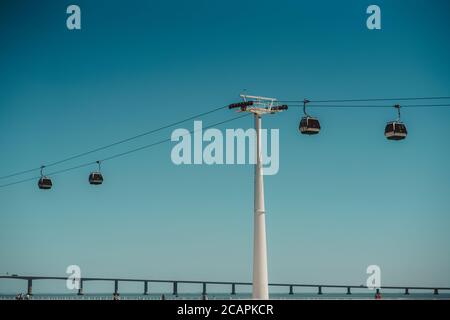 Eine moderne touristische Seilbahn mit vier Autos und einem dicken tragenden Stützrohr vorne, einem blauen klaren Himmel hinten und einer Transportbrücke Stockfoto