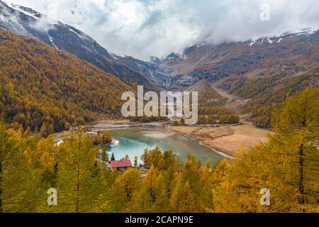 Atemberaubende Luftaufnahme des Palu Sees unterhalb des Piz Palu Gletschers in den Schweizer Alpen auf dem Weg des Sightseeing-Zuges Bernina Express am bewölkten Herbsttag, Kanton Stockfoto