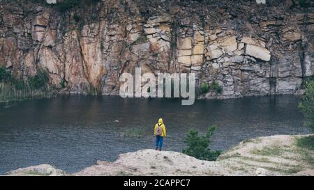 Frau im gelben Regenmantel beim Wandern in der Bergschlucht Stockfoto