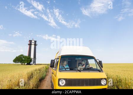 Junges osteuropäisches Paar, das mit einem gelben Wohnmobil durch die Landschaft reist. Selbstgebautes Off-Grid Wohnmobil Camping in der wilden Natur. Stockfoto