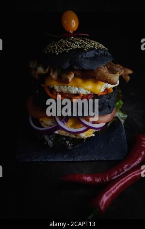 Schwarzer Burger rot Oniondark Hintergrund mit würzigen roten Chili Pfeffer Stockfoto