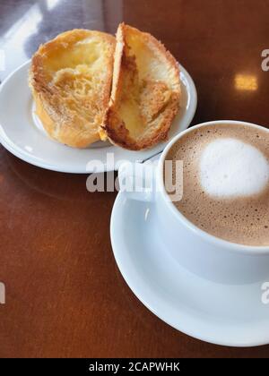 Brasilianisches Frühstück. Cappuccino Tasse und geröstetes Brot mit Butter Hintergrund Stockfoto