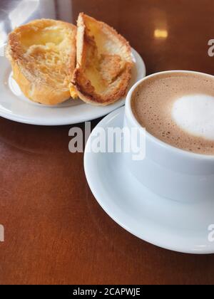 Brasilianisches Frühstück. Cappuccino Tasse und geröstetes Brot mit Butter Hintergrund Stockfoto