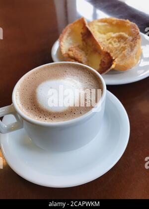 Brasilianisches Frühstück. Cappuccino Tasse und geröstetes Brot mit Butter Hintergrund Stockfoto