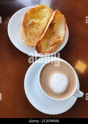 Brasilianisches Frühstück. Cappuccino Tasse und geröstetes Brot mit Butter Hintergrund Stockfoto