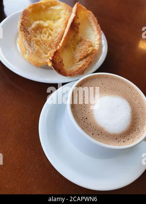 Brasilianisches Frühstück. Cappuccino Tasse und geröstetes Brot mit Butter Hintergrund Stockfoto