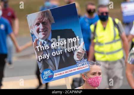 Basildon, Essex, Großbritannien. August 2020. In Basildon fand ein demonstrationszug statt, der gegen den Ausschluss des Personals des nationalen Gesundheitsdienstes aus der Lohnerhöhung des öffentlichen Sektors protestierte. Die Demonstranten versammelten sich im Basildon Hospital, bevor sie in das Stadtzentrum von Basildon marschierten, wo viele Blumen und Bänder für die vielen Gesundheitshelfer, die durch die COVID-19 Coronavirus-Pandemie verloren wurden, hinlegten Stockfoto