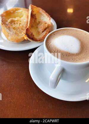 Brasilianisches Frühstück. Cappuccino Tasse und geröstetes Brot mit Butter Hintergrund Stockfoto