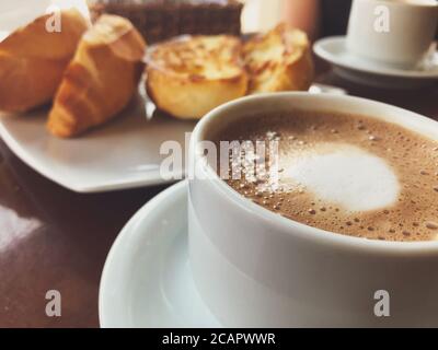 Brasilianisches Frühstück. Cappuccino Tasse und geröstetes Brot mit Butter Hintergrund Stockfoto