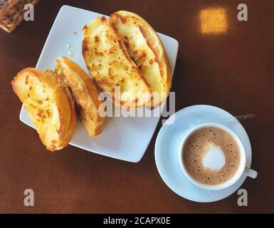 Brasilianisches Frühstück. Cappuccino Tasse und geröstetes Brot mit Butter Hintergrund Stockfoto