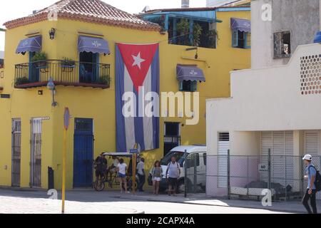 Straßenszene in Havanna, Kuba mit gelbem Haus mit kubanischer Flagge Stockfoto