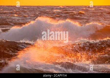 Krachende Wellen bei Sonnenuntergang über Lake Superior, Wawa, Ontario, Kanada Stockfoto