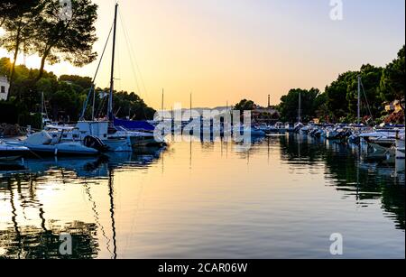Santa Ponsa, Mallorca, Spanien. Sonnenuntergang mit orangefarbener Sonne im Hafen mit Segelbooten, Booten. Stockfoto