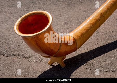 Eine Nahaufnahme des Endes des hölzernen Alphorns (Alpenhorn oder Alpenhorn) auf einem betonierten Hintergrund. Traditionelles Instrument in der Schweiz Stockfoto