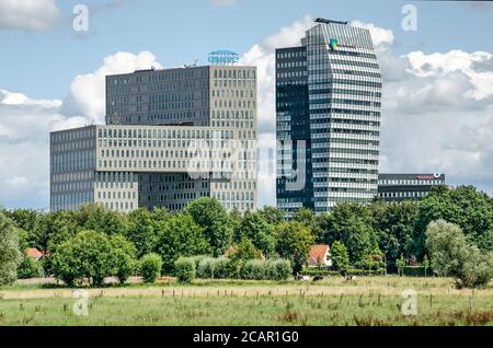 Zwolle, Niederlande, 21. Juli 2020: Fernansicht von zwei großen, modernen Bürogebäuden in Voorsterpoort, mit einer kontrastierenden ländlichen Wohnanlage Stockfoto