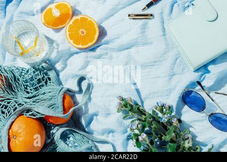 Sommer Picknick Flatlay von Früchten, Blumen und Zitronenwasser auf einer blauen Decke Stockfoto