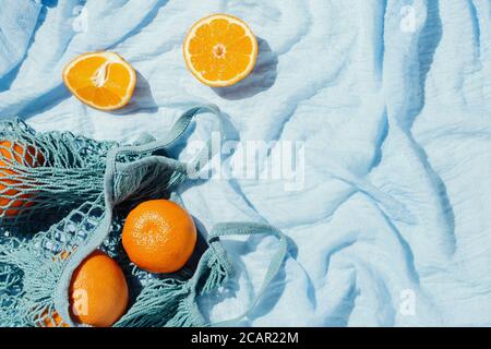 Picknick-Flatlay von Orangen in einer Öko-Saite auf Blaue Decke Stockfoto